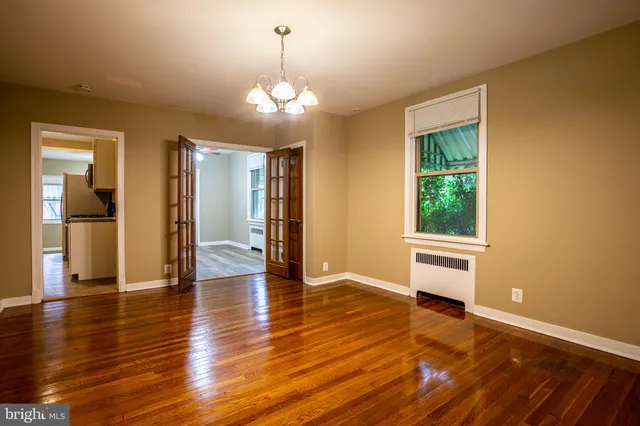 a view of a livingroom with wooden floor and a kitchen