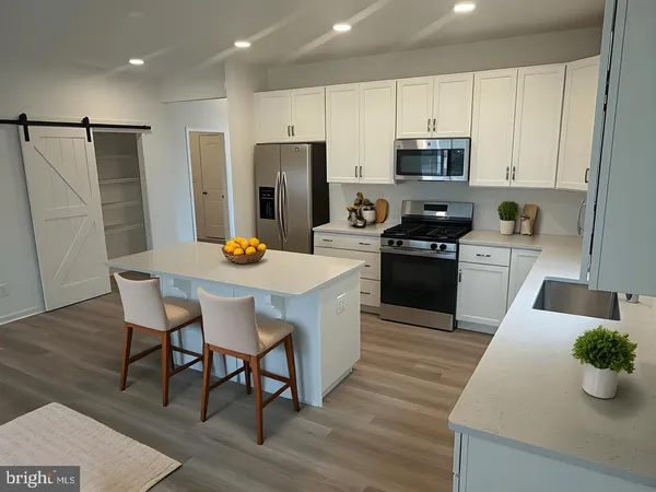 a kitchen with stainless steel appliances a dining table chairs refrigerator and microwave