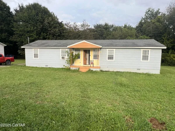 a front view of a house with a yard and trees