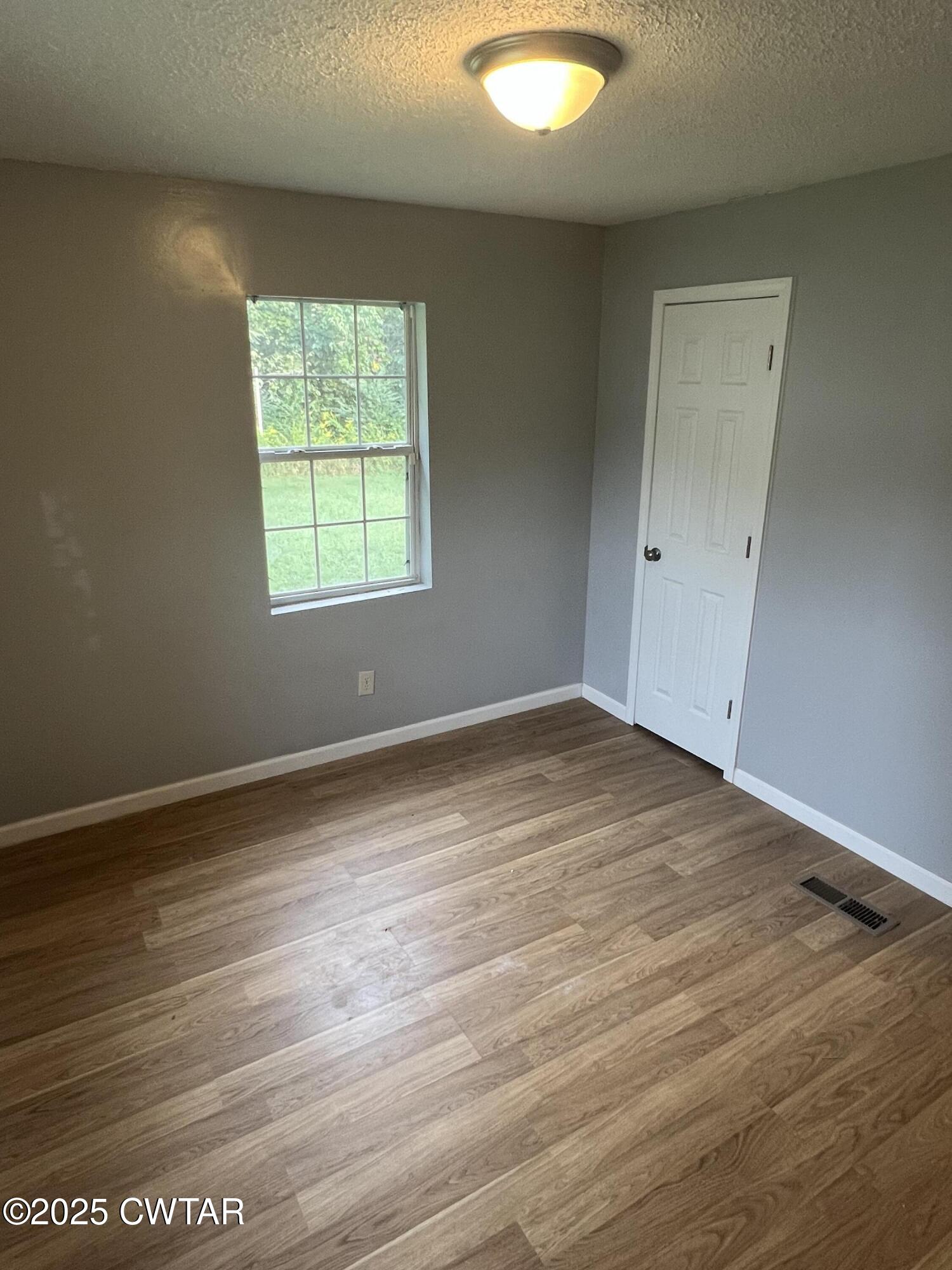 134 Liddon Street Jackson, TN 38301 - Photo 11 of 13 an empty room with wooden floor and windows
