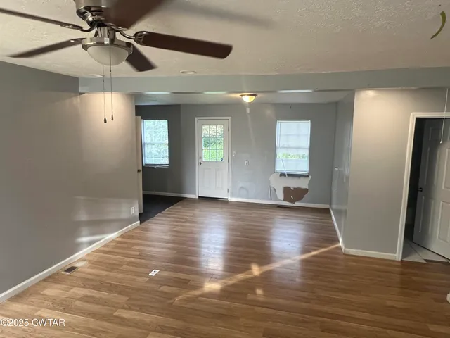 a view of an empty room with window and wooden floor
