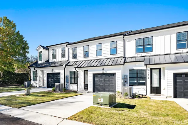 a view of a house with small yard plants and large tree