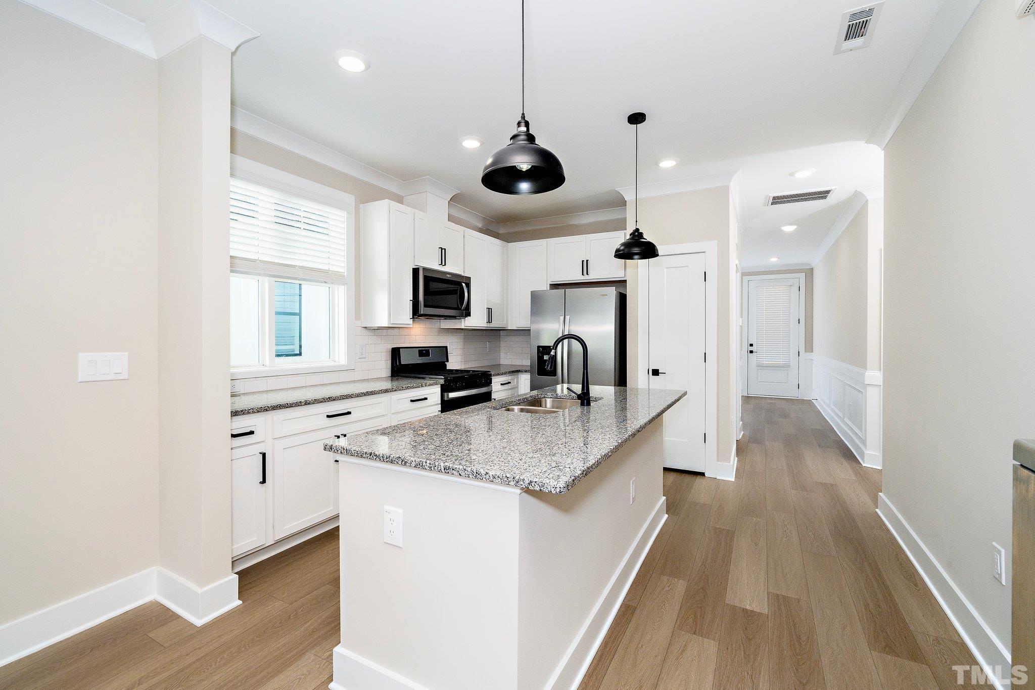6104 Fox Raleigh, NC 27616 - Photo 36 of 54 a kitchen with stainless steel appliances granite countertop a sink a stove and a wooden floors