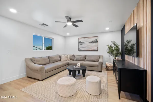 a living room with furniture a flat screen tv and a ceiling fan