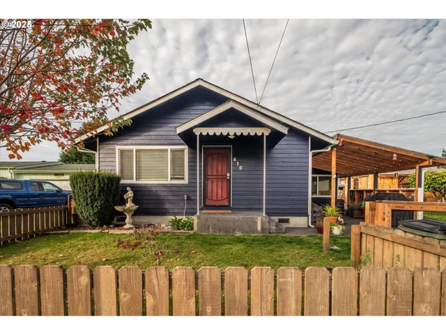 a view of a house with wooden fence next to a yard