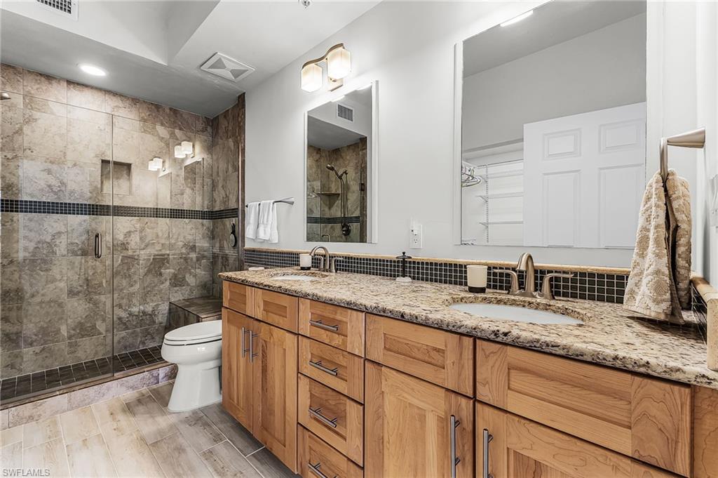 401 Bayfront Place, Unit 3405 Naples, FL 34102 - Photo 19 of 31 a bathroom with a granite countertop sink a toilet a mirror and shower