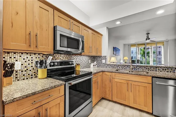 a kitchen with granite countertop a sink stove and microwave