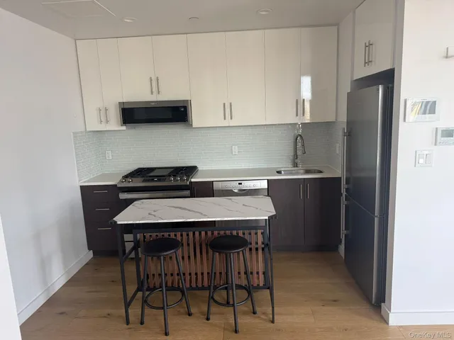 a kitchen with stainless steel appliances a table chairs sink and cabinets