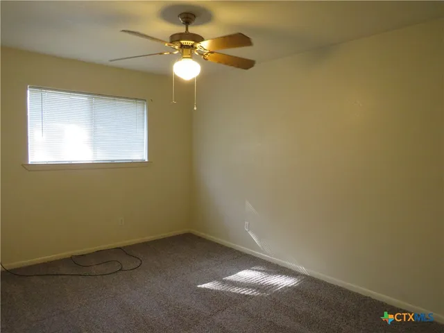 an empty room with a window and a fan