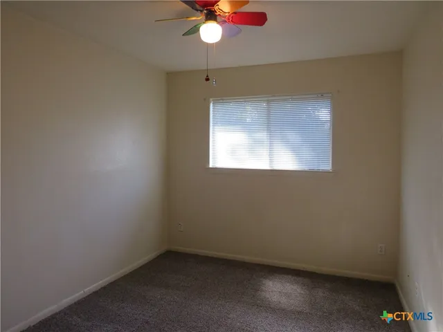 an empty room with a window and a fan