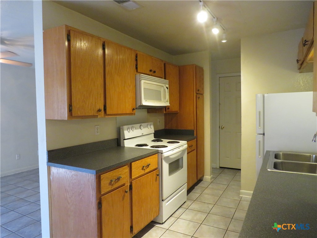8221 Sam Rayburn Drive, Unit 103 Austin, TX 78753 - Photo 6 of 15 a kitchen with a stove a sink and a refrigerator