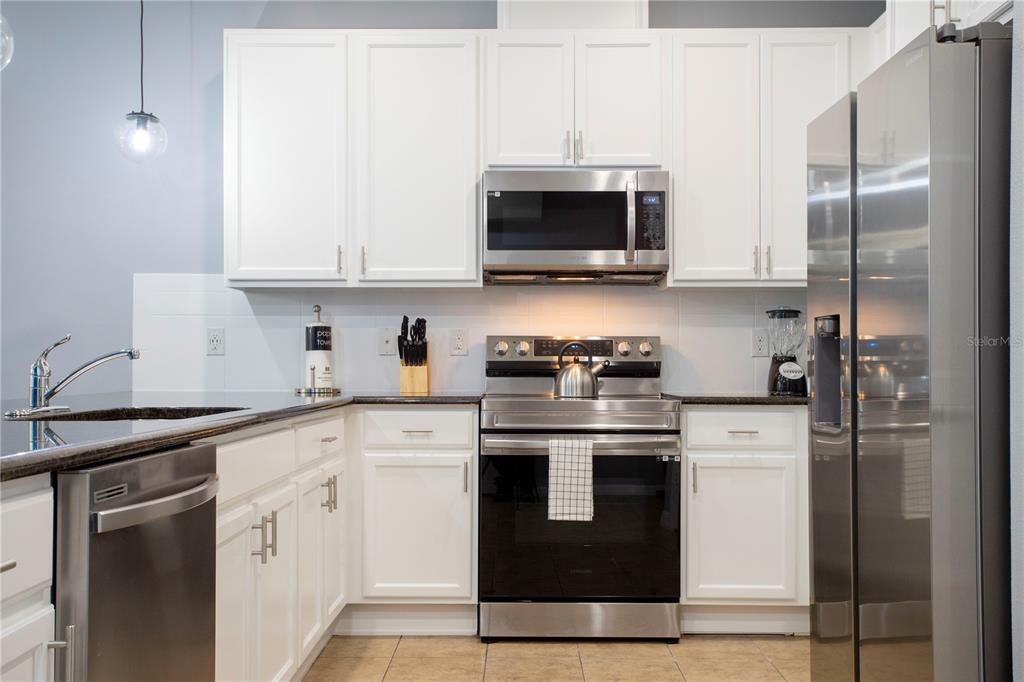 3181 Tocoa Circle Kissimmee, FL 34746 - Photo 18 of 87 a kitchen with stainless steel appliances granite countertop a stove a refrigerator and a microwave