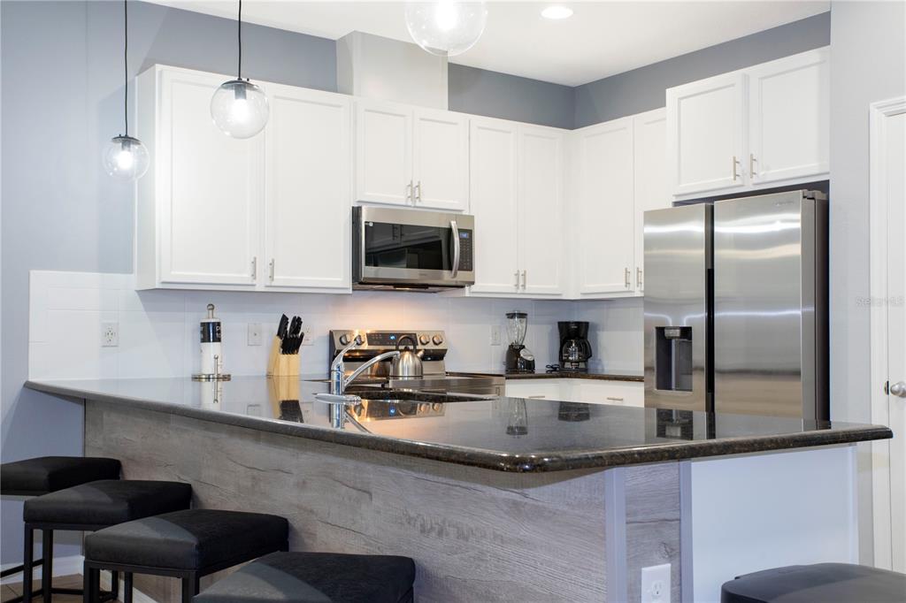 3181 Tocoa Circle Kissimmee, FL 34746 - Photo 19 of 87 a kitchen with stainless steel appliances granite countertop a sink a microwave a refrigerator and cabinets