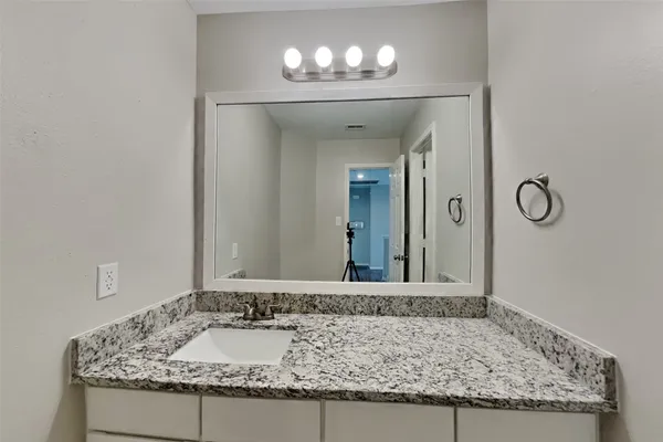 a bathroom with a granite countertop sink and a mirror