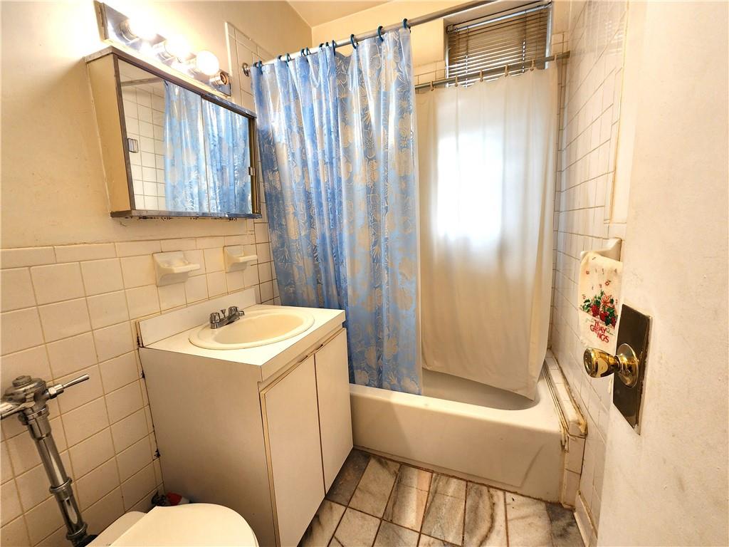 8735 Bay Parkway, Unit A57 Brooklyn, NY 11214 - Photo 8 of 13 a bathroom with a sink a toilet and shower