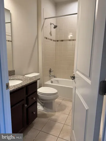 a bathroom with a granite countertop bathtub shower sink vanity and toilet