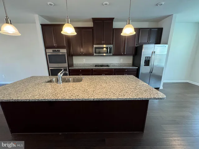 a kitchen with kitchen island granite countertop a sink a counter top space a cabinets and appliances