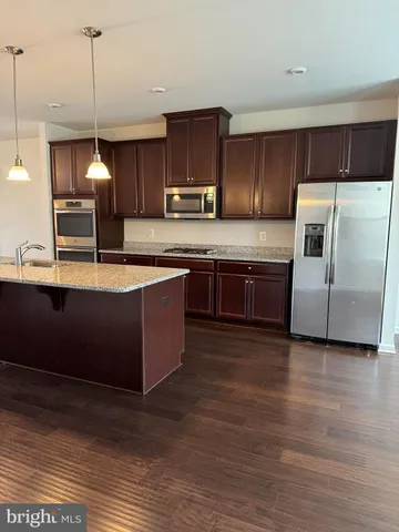 a kitchen with stainless steel appliances granite countertop a sink a stove and a wooden floors