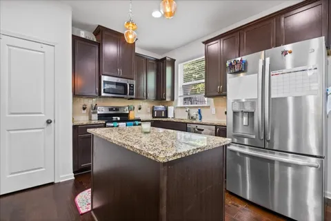 a kitchen with stainless steel appliances granite countertop a refrigerator a stove a sink and a microwave