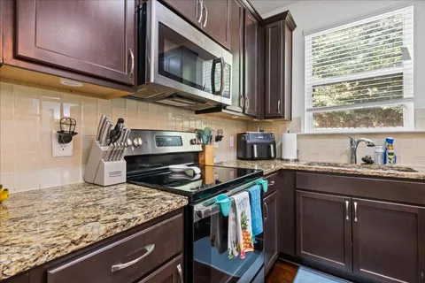 a kitchen with stainless steel appliances granite countertop a stove a sink and a microwave