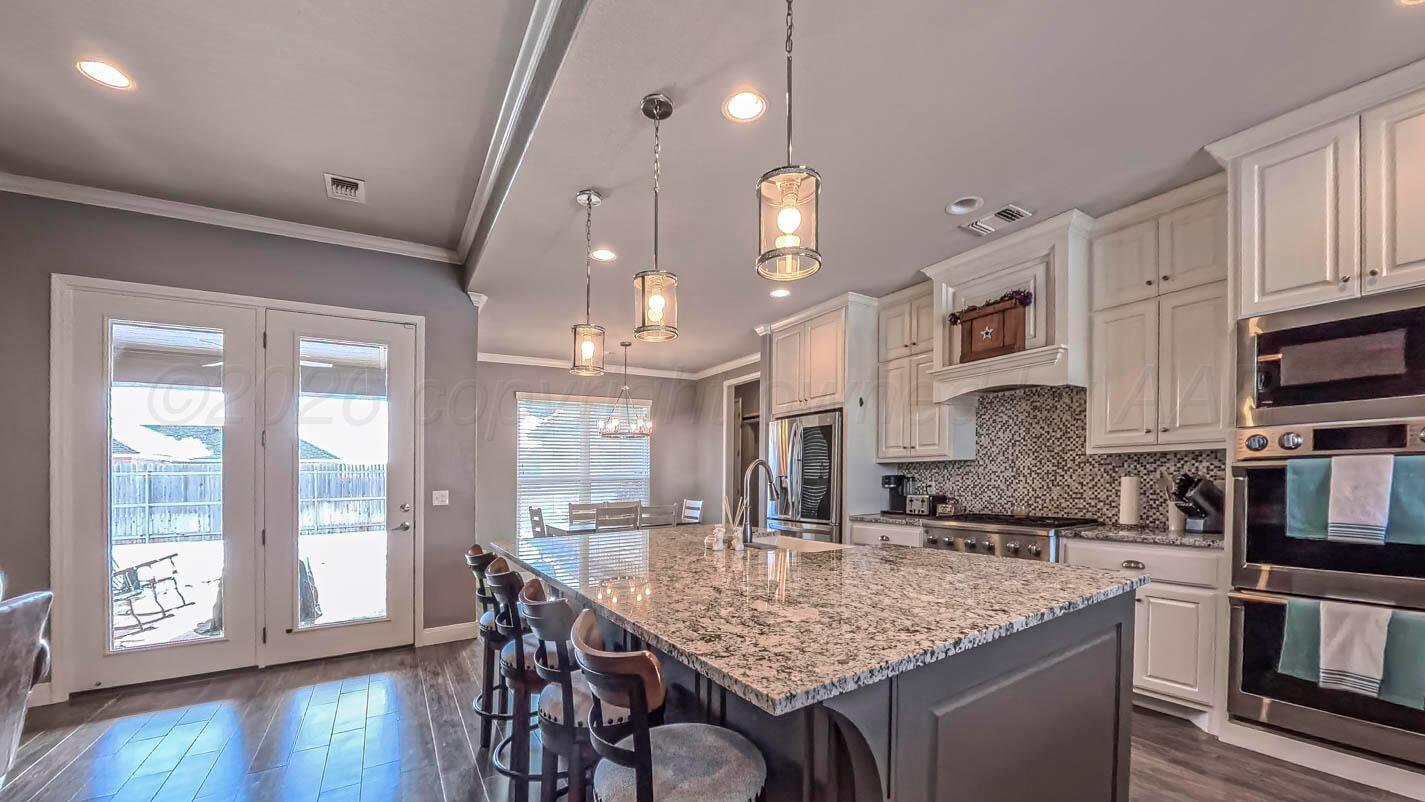 8903 Canton Court Amarillo, TX 79119 - Photo 4 of 26 a kitchen with stainless steel appliances granite countertop a sink a stove and a wooden floors