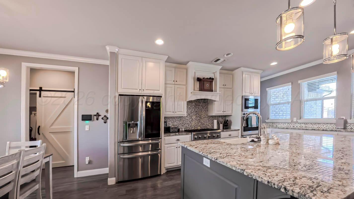 8903 Canton Court Amarillo, TX 79119 - Photo 5 of 26 a kitchen with stainless steel appliances granite countertop a refrigerator a stove and a sink with wooden floor