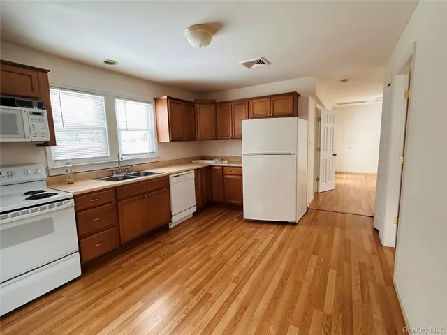 a kitchen with wooden floors and white stainless steel appliances