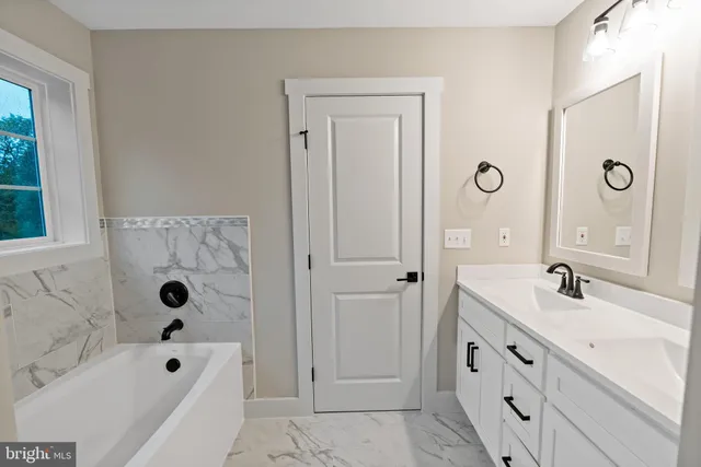 a bathroom with a tub a sink and a mirror