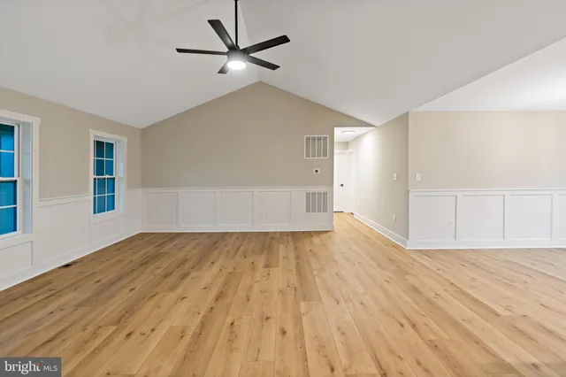 an empty room with wooden floor and windows