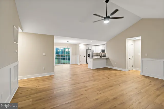 a view of empty room with wooden floor and ceiling fan