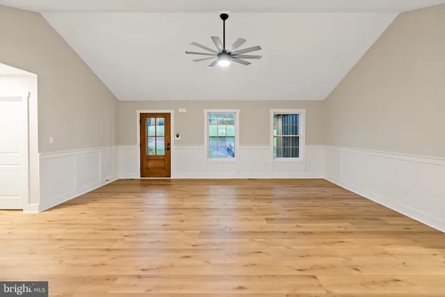 a view of an empty room with window and wooden floor