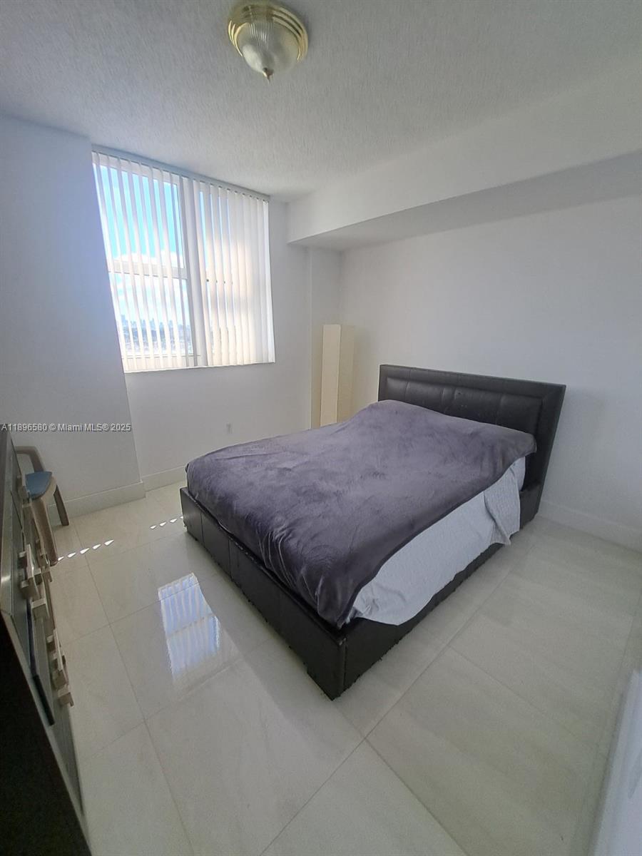 5077 Northwest 7th Street, Unit PH17 Miami, FL 33126 - Photo 3 of 25 a bed sitting in a room next to a window
