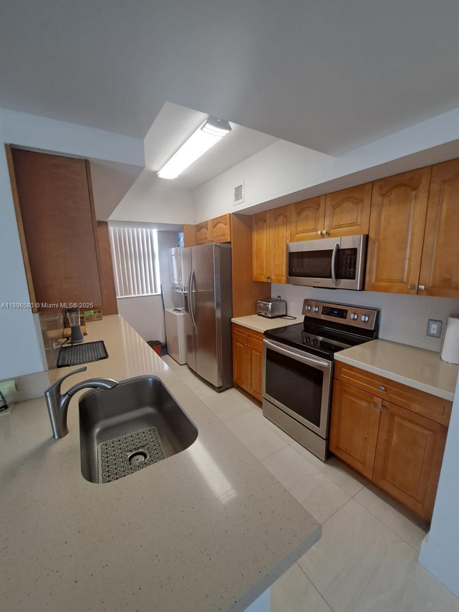 5077 Northwest 7th Street, Unit PH17 Miami, FL 33126 - Photo 4 of 25 a kitchen with stainless steel appliances a sink a stove and cabinets