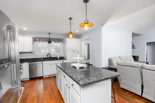 a kitchen with stainless steel appliances granite countertop a sink dishwasher and a stove with wooden floor