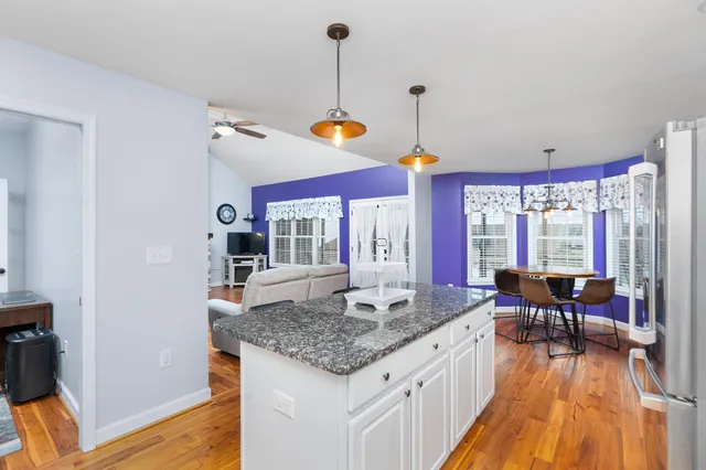 a kitchen with granite countertop sink stove and wooden floor