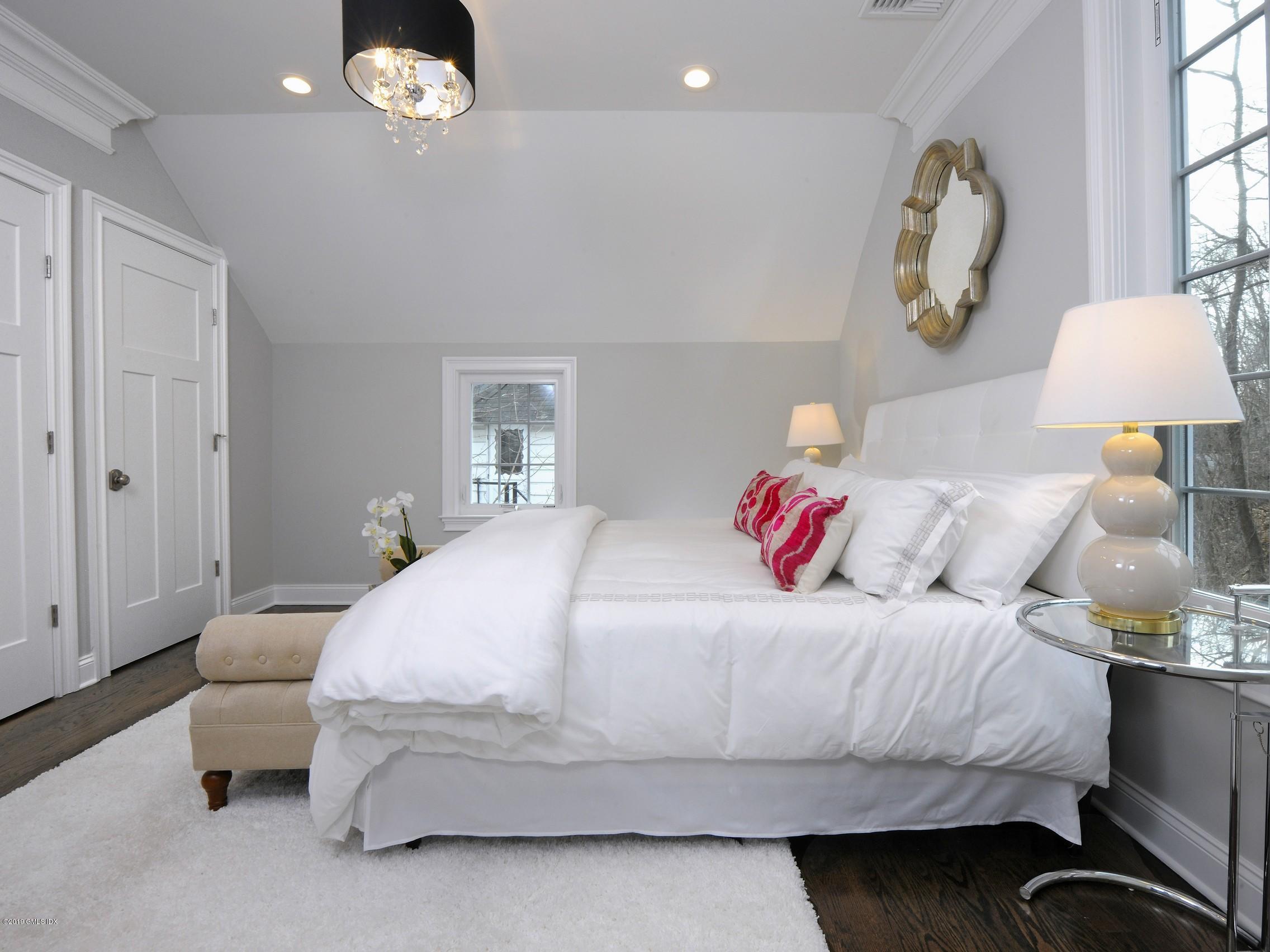 200 Davis Avenue Greenwich, CT 06830 - Photo 19 of 26 a bedroom with a bed and a chandelier