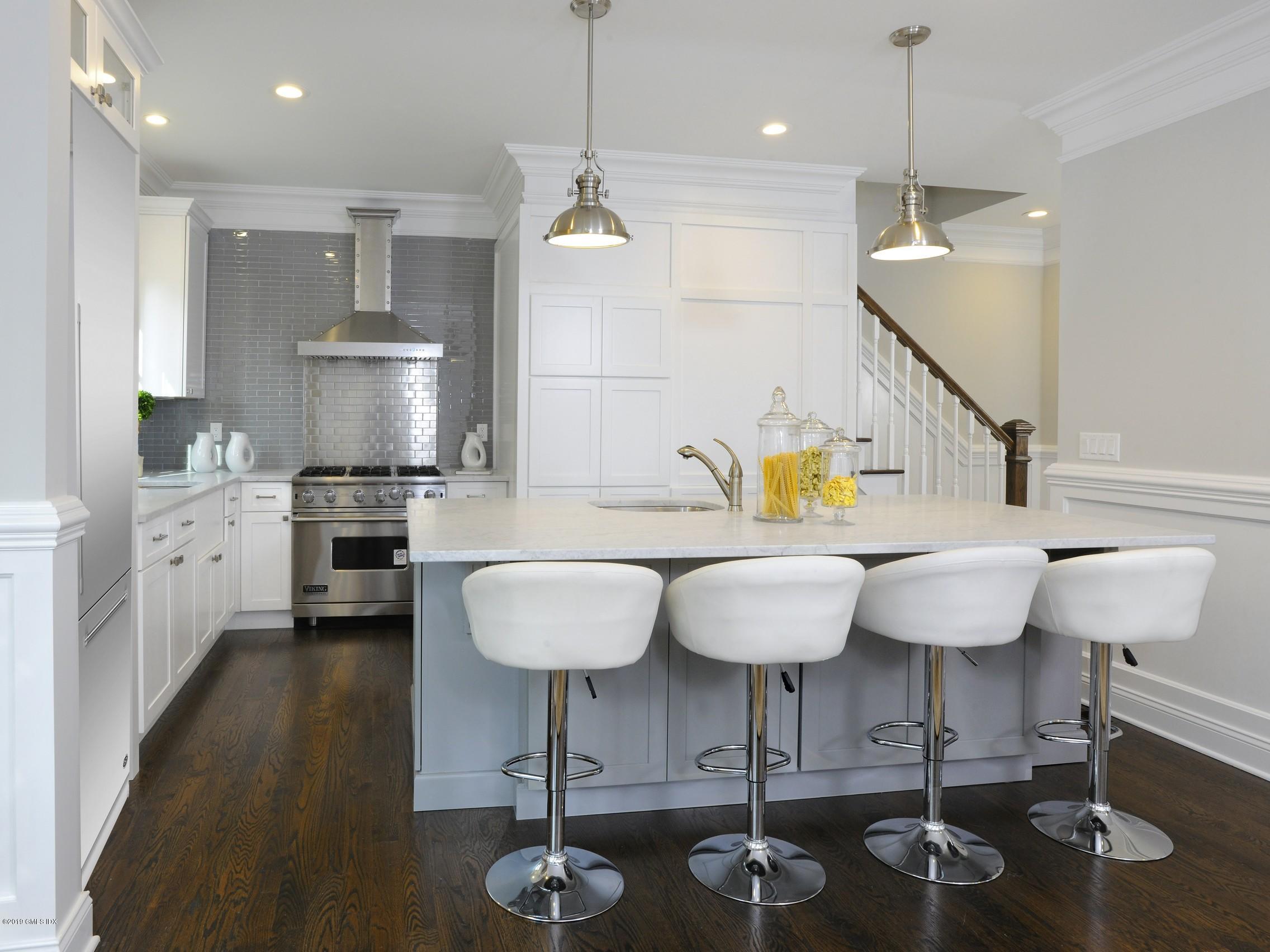 200 Davis Avenue Greenwich, CT 06830 - Photo 9 of 26 a kitchen with stainless steel appliances kitchen island granite countertop a table chairs in it and wooden floors