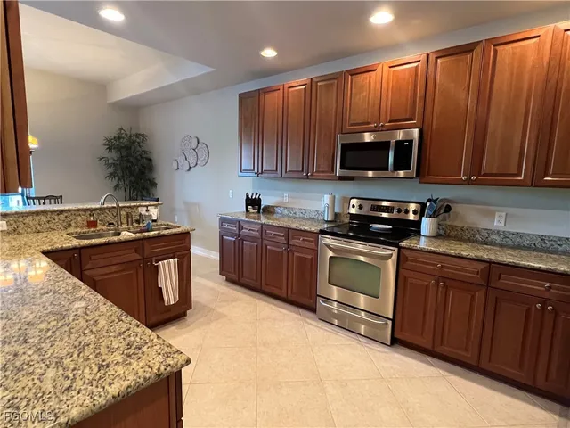 a kitchen with stainless steel appliances granite countertop wooden cabinets a stove top oven a sink and dishwasher