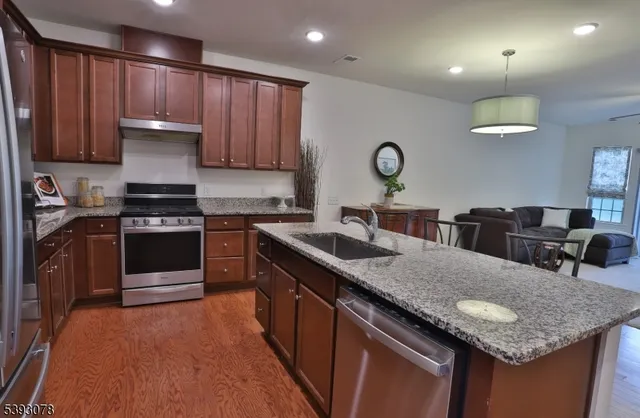 a kitchen with granite countertop a stove a sink dishwasher and cabinets with wooden floor