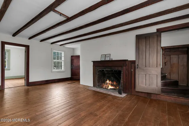 a view of an empty room with wooden floor fireplace and a window