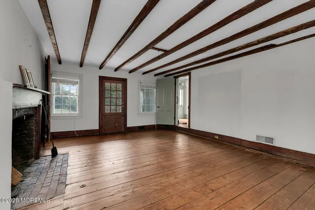 a view of empty room with wooden floor and fireplace