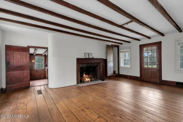 a view of an empty room with wooden floor fireplace and a window