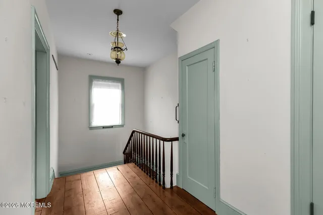 an empty room that has a window and wooden floor