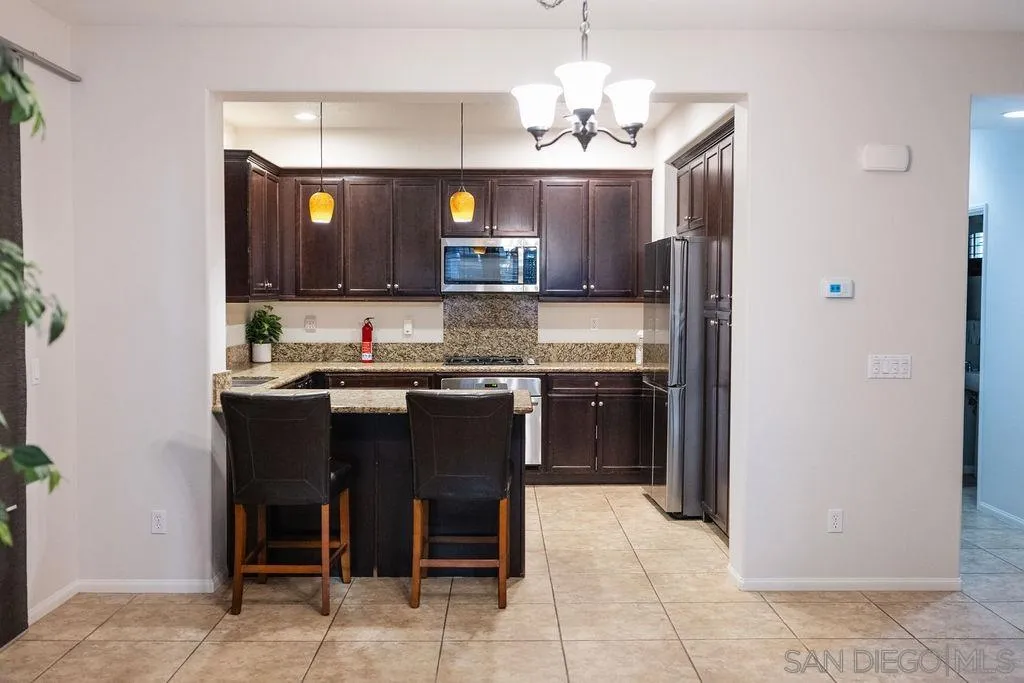 1808 Cyan Lane Chula Vista, CA 91913 - Photo 17 of 43 a kitchen with kitchen island granite countertop a sink cabinets and stainless steel appliances