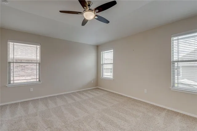 an empty room with ceiling fan and window