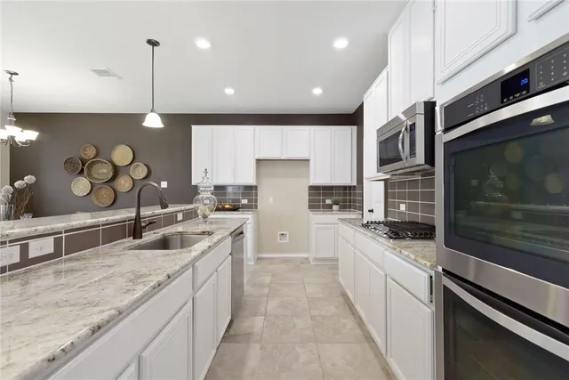 a large kitchen with stainless steel appliances kitchen island granite countertop a sink a stove and a wooden cabinets