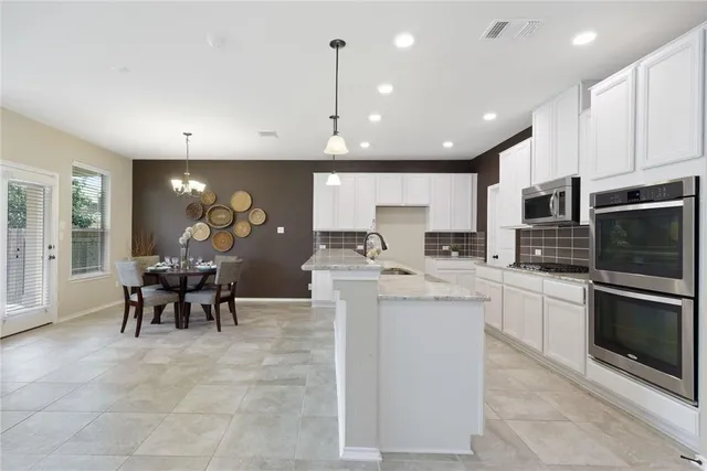 a kitchen with kitchen island stainless steel appliances a table and chairs in it