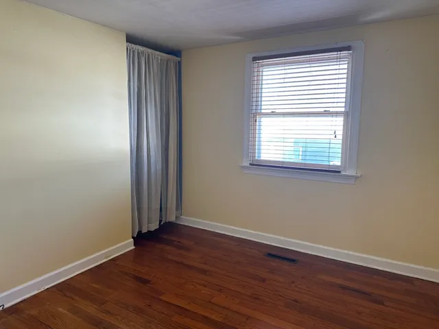 an empty room with wooden floor and a window