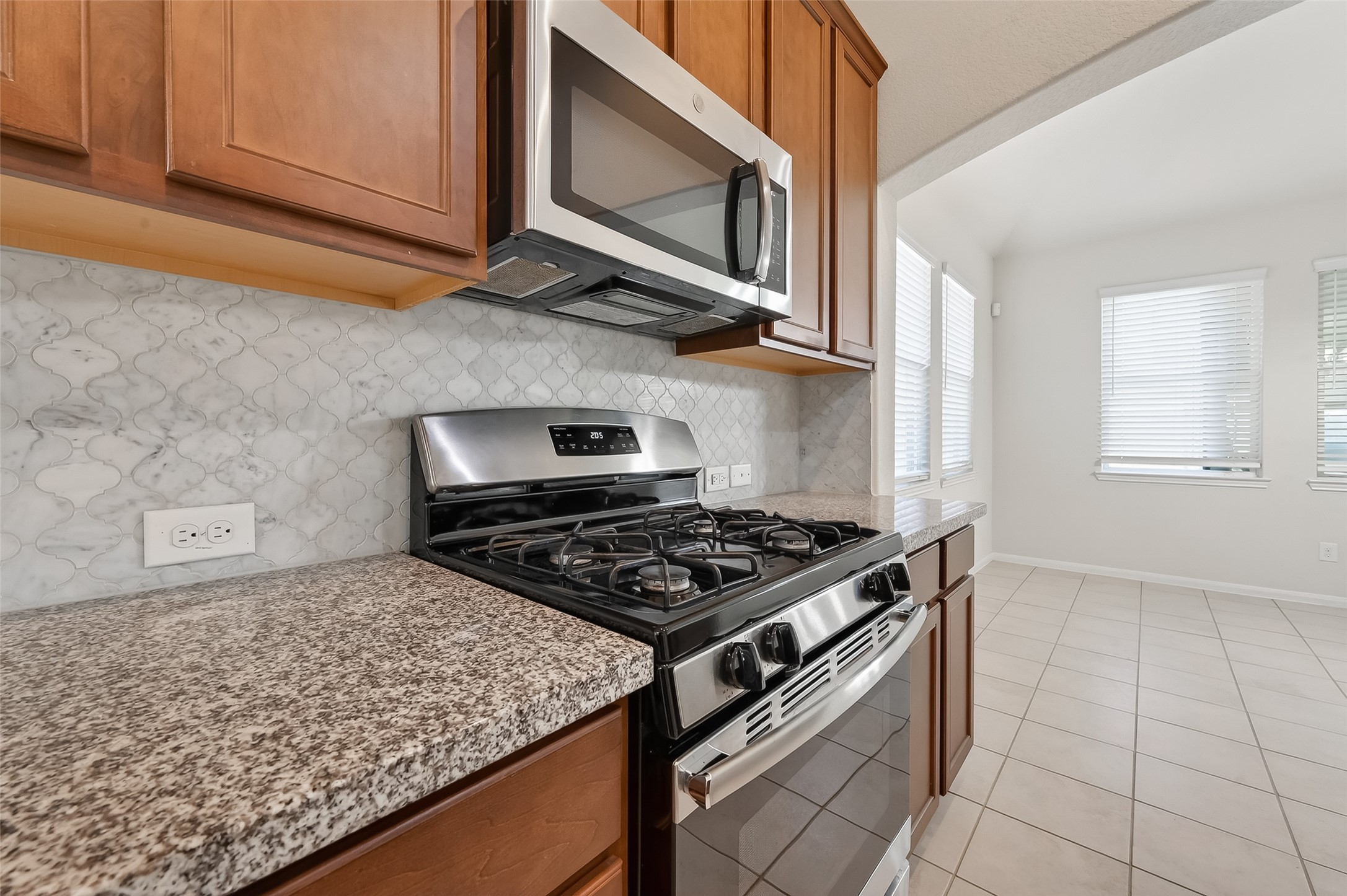 7631 Granite Terrace Lane Houston, TX 77083 - Photo 22 of 46 Modern kitchen with stainless steel appliances, granite countertops, and a stylish tile backsplash.