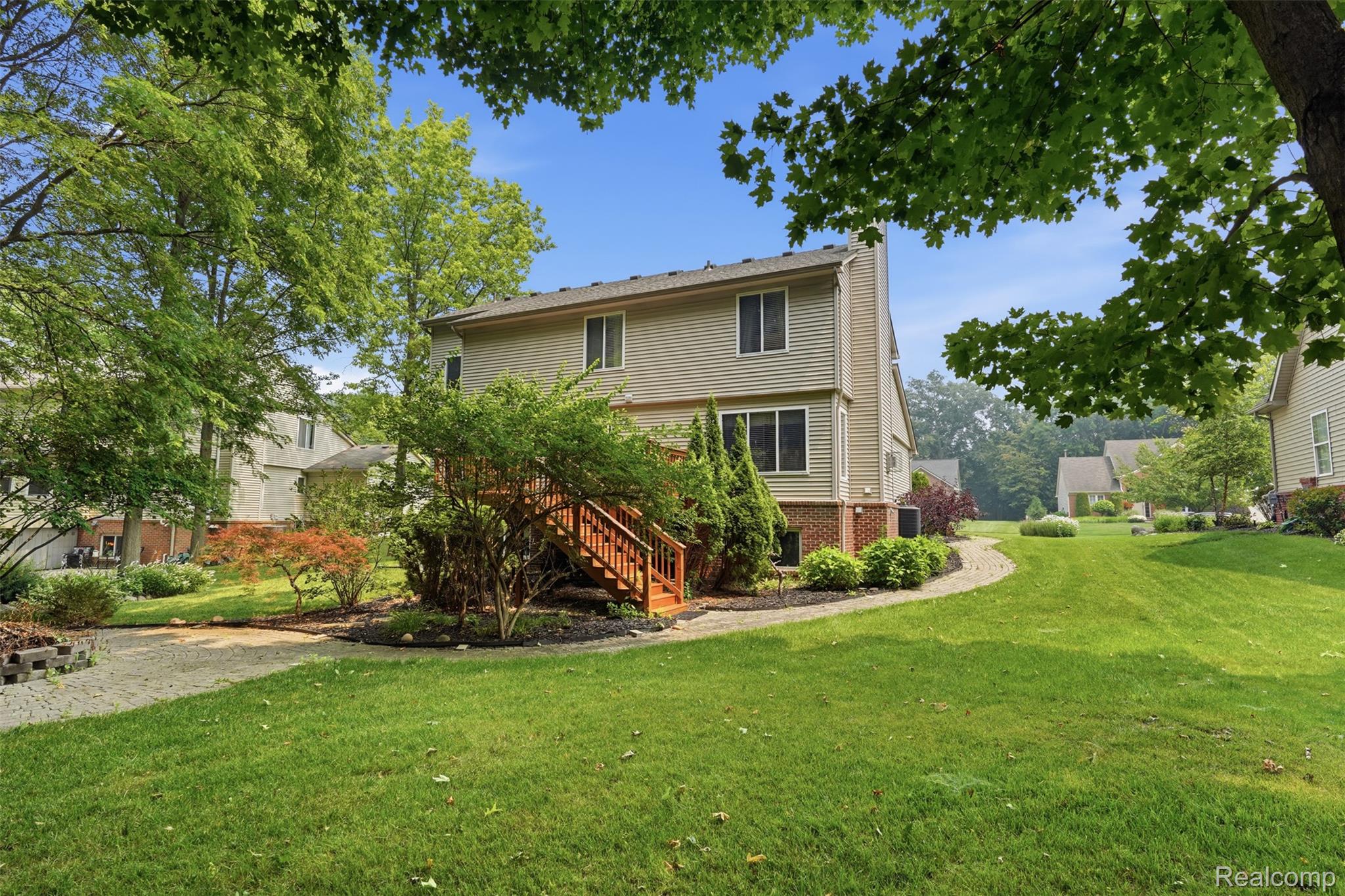 170 Fairhill Way Howell, MI 48843 - Photo 42 of 46 Rear exterior featuring tan siding, a multi-level wood deck, established landscaping, and a manicured lawn